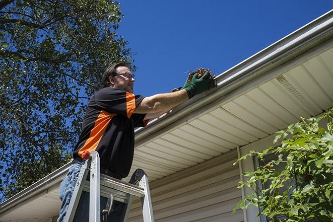 smiling worker fixing gutters on a residential home in Aston, PA